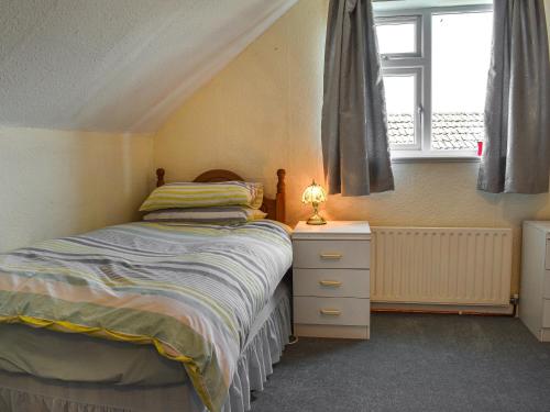 a bedroom with a bed and a dresser and a window at Teazles in Peel