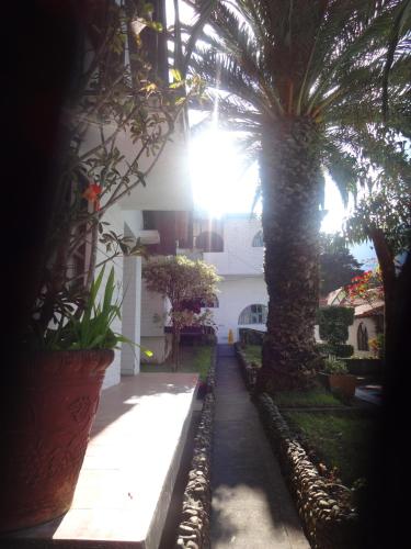 a courtyard with palm trees and a white building at Hosteria Casa Giralda in Baños