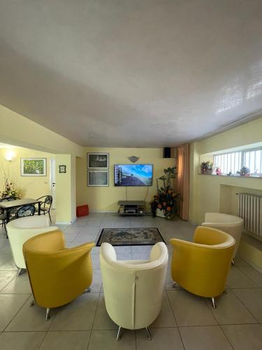 a living room with yellow chairs and a flat screen tv at Hotel La Terrazza in Porto San Giorgio