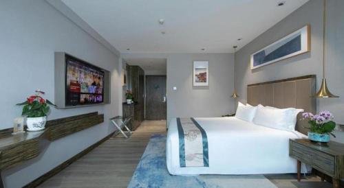a hotel room with a large bed and a television at Landmark Hotel in Zhuhai