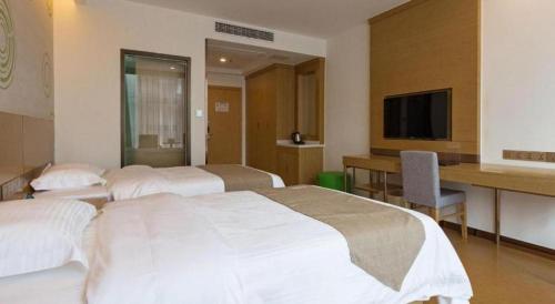a hotel room with two beds and a desk and a television at GreenTree Inn Nantong University Industrial Expo City Express Hotel in Nantong