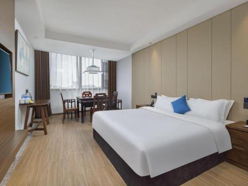 a hotel room with a large white bed and a table at GME Taizhou Jingjiang City Bus Station Hotel in Jingjiang