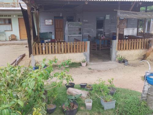 a house with a fence and plants in front of it at Bunda Homestay and Garden Warung 