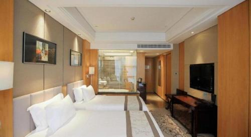 a bedroom with a large white bed and a television at Zhangjiagang Zhonglian GDH International Hotel in Zhangjiagang