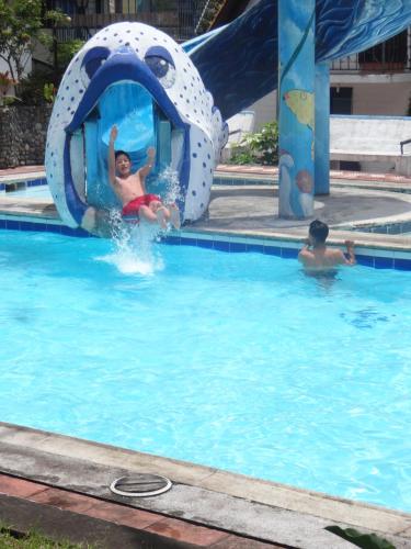 two people in a pool on a water slide at Hosteria Casa Giralda in Baños