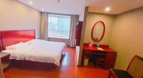 a bedroom with a bed and a desk and a mirror at GreenTree Inn Ganzhou Sankang Temple DaRunFa Express Hotel in Ganzhou