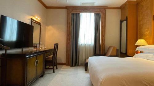 a hotel room with a bed and a flat screen tv at Xiamen Airlines Quanzhou Hotel in Quanzhou