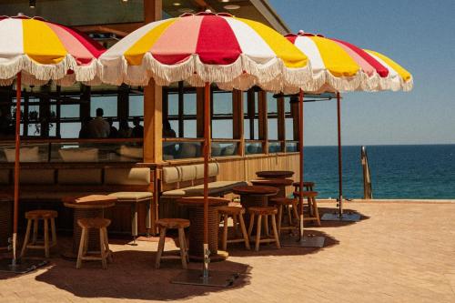 a group of tables and chairs under umbrellas on a beach at Spacious, ocean-front, pied-à-terre with stunning views &opposite cafes in Perth