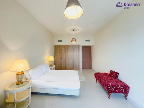 a bedroom with a white bed and a red couch at Dream Inn Apartments - Luxury 2 BR Mina Al Fajer - Harbor View - Al Fujairah in Rūl Ḑadnā