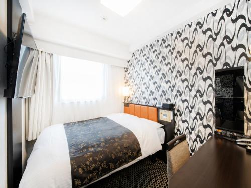 a hotel room with a bed and a wall at APA Hotel Hakata Higashihieekimae in Fukuoka