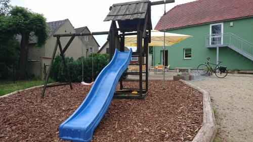 a playground with a blue slide in a yard at Heidebistro in Commerau