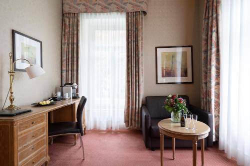a hotel room with a desk and a chair and a table at Grand Hotel Beau Rivage Interlaken in Interlaken