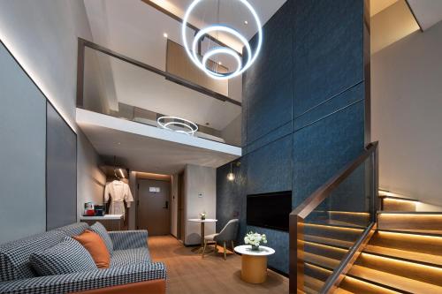a living room with a blue wall and a staircase at Jinglai Hotel Light Luxury - Daning International Shanghai Business School Branch in Shanghai