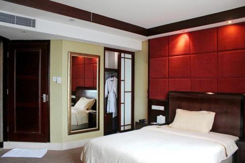 a bedroom with a large bed and a mirror at Chinflux Mandarin Hotel in Dongguan