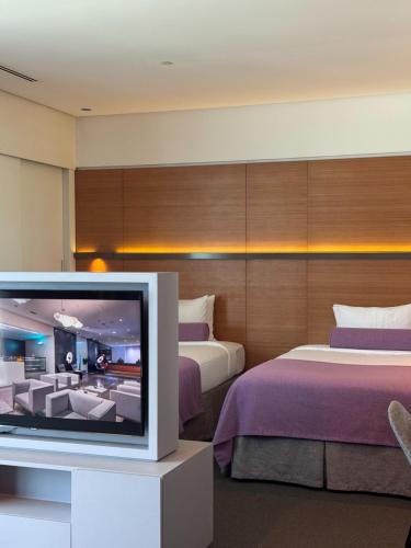 a hotel room with two beds and a television at The Act Hotel Sharjah in Sharjah