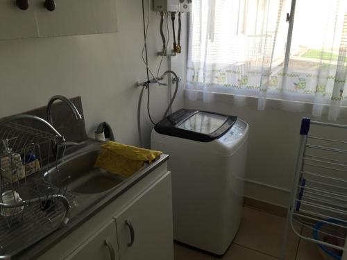 y baño con lavabo y lavadora. en Acogedor departamento cerca del mar, en La Serena