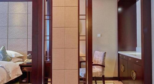 a bedroom with a bed and a desk and a chair at Huangshan International Hotel in Huangshan