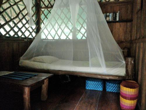 a bed in a room with a net at El Hotelito Perdido in Rio Dulce