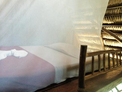 a bed in a room with a curtain at El Hotelito Perdido in Rio Dulce