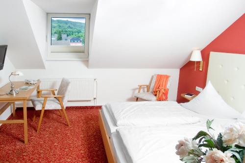a room with two beds and a table and a window at Hotel Koch Schilt in Irrel