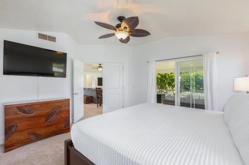 a white bedroom with a bed and a flat screen tv at Pili Aloha in Princeville