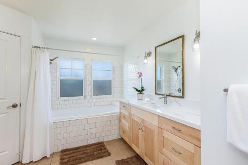 a bathroom with a tub and a sink and a mirror at Pili Aloha in Princeville