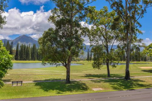 a park with a bench and a lake and trees at Pili Aloha in Princeville