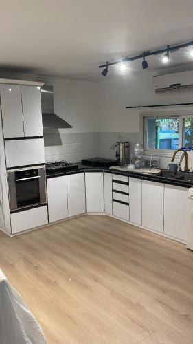 a kitchen with white cabinets and a wooden floor at הוילה הצפונית in Kefar Zetim