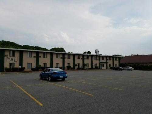 a blue car parked in a parking lot in front of a building at Woonsocket Motor Inn in Woonsocket