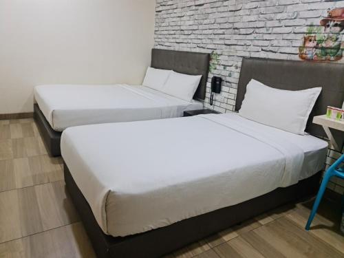 two beds in a room with a brick wall at 888 Boutique Hotel in Batu Pahat