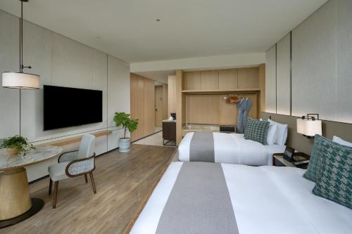 a hotel room with a bed and a flat screen tv at Grand Ocean View Hotel Zhuhai in Zhuhai