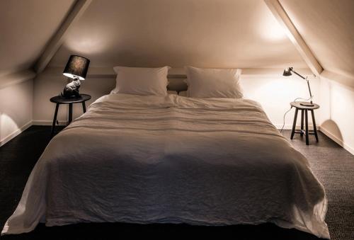 a bedroom with a large white bed with two tables at Het Witte Kasteel in Loon op Zand
