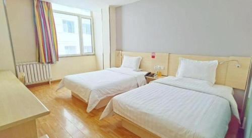 a hotel room with two beds and a window at 7 Days Inn Hohhot Hailiang Xinhua Square Metro Station in Hohhot