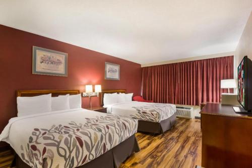 ein Hotelzimmer mit zwei Betten und einem Fernseher in der Unterkunft Red Roof Inn Winchester - Lexington East in Winchester