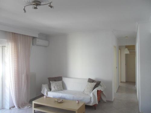 a living room with a white couch and a table at Comfortable Thermi apartment near SKG Airport in Thérmi