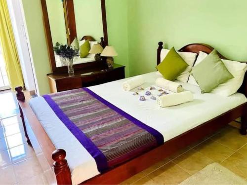 a bedroom with a large bed with green walls at Velapura River Garden in Kalutara