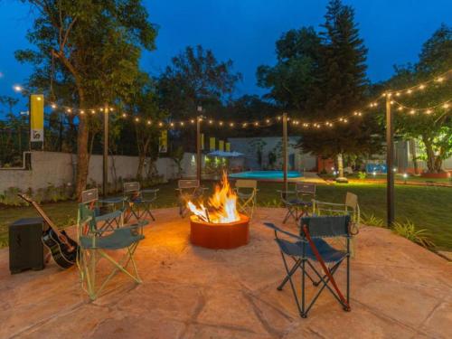 a fire pit in a patio with chairs and lights at The Hosteller Lonavala, City Centre in Lonavala