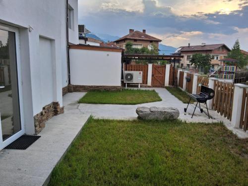a patio with a chair and a rock in a yard at Белчини in Dobrinishte