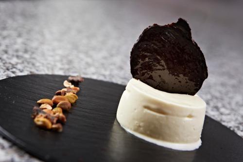 a piece of food on top of a black plate at Hôtel Mets et Plaisirs in Mazamet