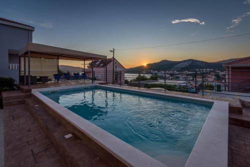 a swimming pool with a sunset in the background at Nice apartment with private heated pool in Villa Lahor in Seget Vranjica