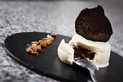 a piece of cake on a black plate with a spoon at Hôtel Mets et Plaisirs in Mazamet