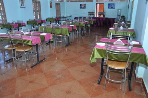 a room with tables and chairs with pink and green tables at Parkinternational in Kovalam