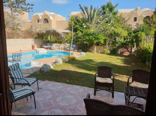 a patio with chairs and a swimming pool at Sou Villa in El Alamein