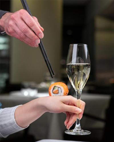 a person holding a glass of wine and a donut at Grand Hyatt Berlin in Berlin