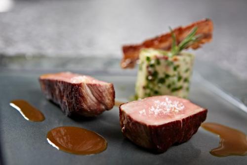 a piece of meat sitting on a plate with sauce at Hôtel Mets et Plaisirs in Mazamet
