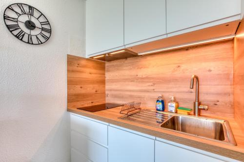 une cuisine avec un évier et une horloge murale dans l'établissement Appartement à 70m de la plage, à La Grande Motte