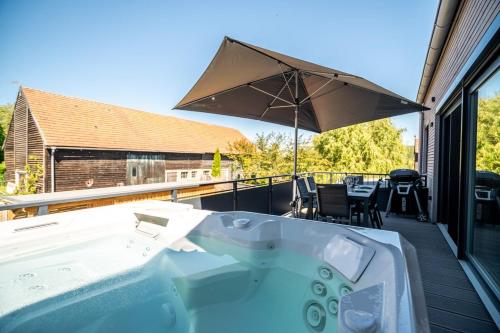a hot tub on a deck with an umbrella at Ferienwohnung ScheunenBlick in Göhren-Lebbin