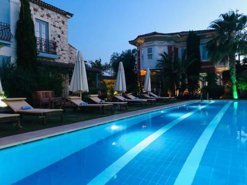 a swimming pool with chairs and umbrellas next to a building at On Oda Alaçatı in Alaçatı