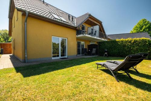 a yard with a chair in front of a house at One Putt Erdgeschoss in Göhren-Lebbin