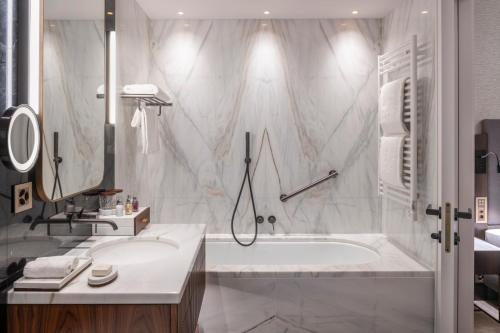 a white bathroom with a tub and a sink at Grand Hotel des Bains Kempinski in St. Moritz